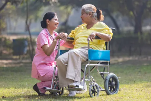 A caregiver from Adarsh Nursing Bureau smiling with an elderly patient at home
